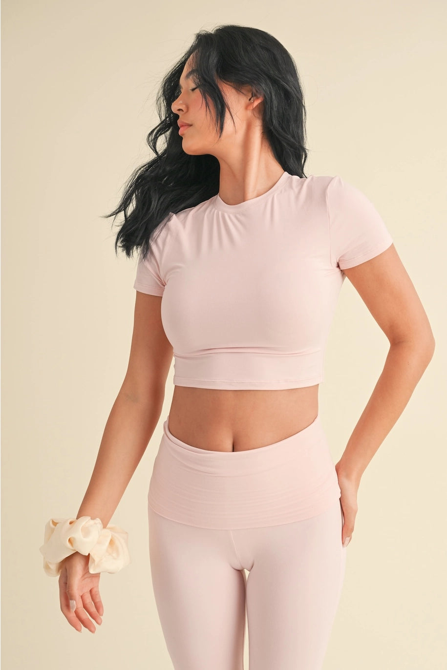 Woman wearing a light pink athletic outfit on a beige background