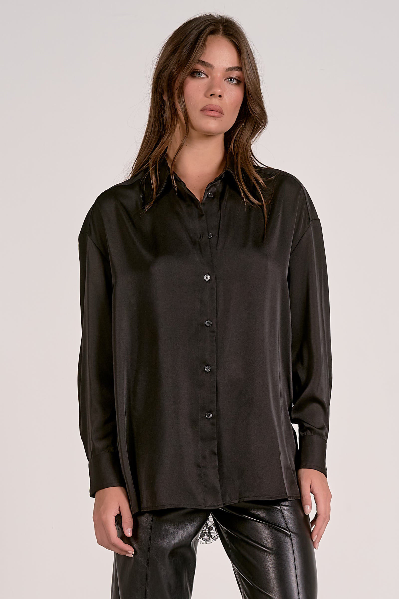 Woman wearing a black satin shirt against a plain background