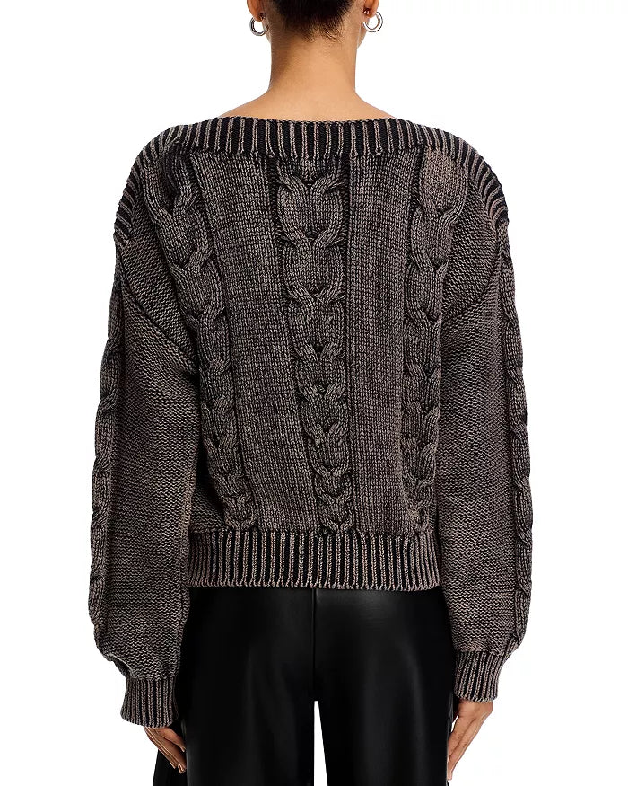 Person wearing a dark gray cable knit sweater on a white background