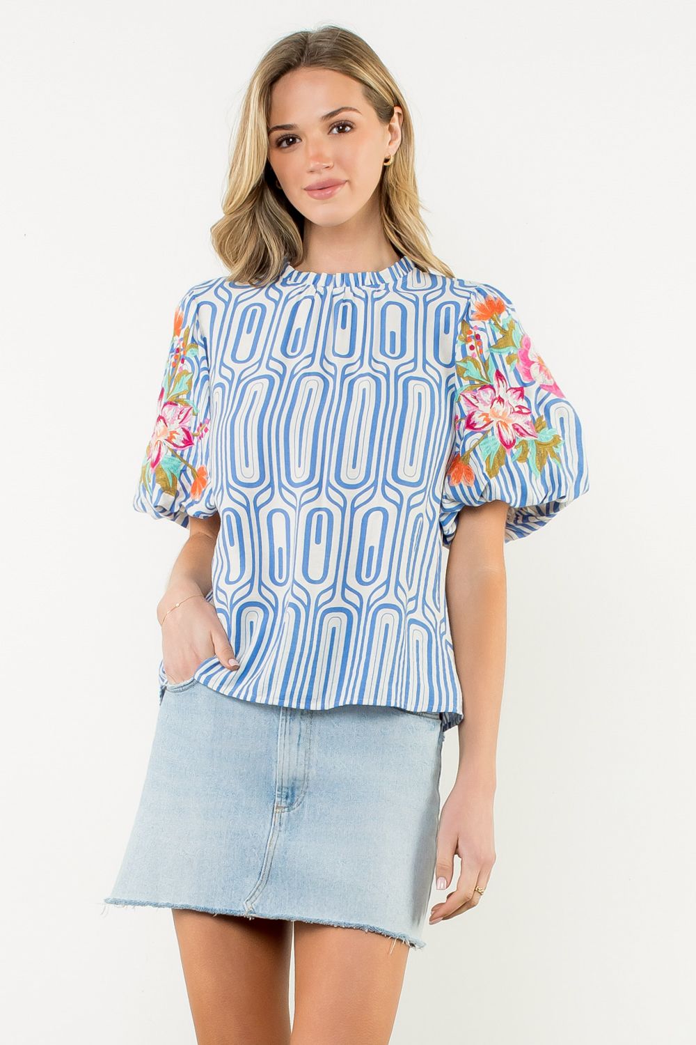Woman wearing a blue patterned blouse with floral sleeves on a white background