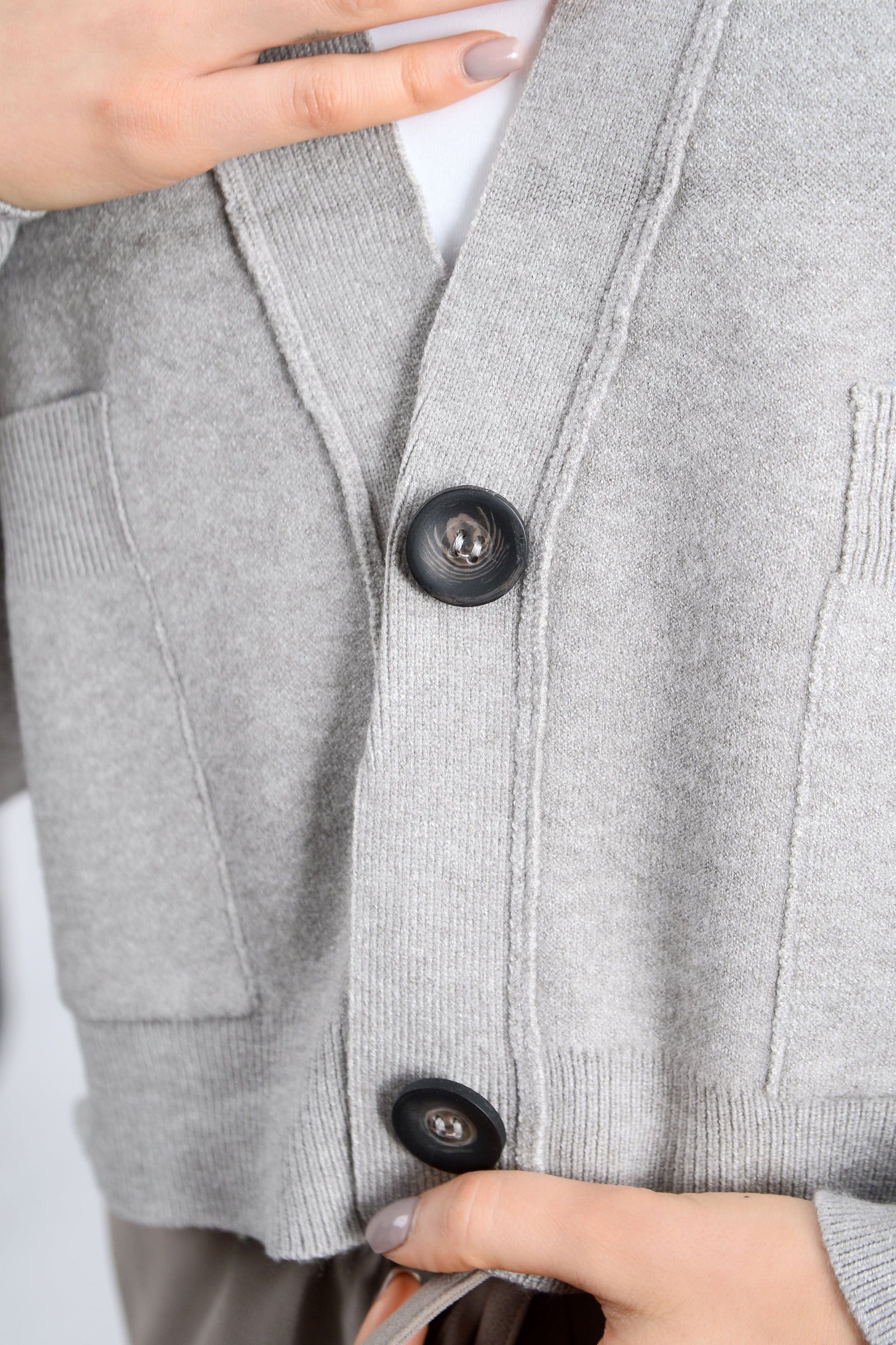 Close-up of a gray cardigan with buttons being adjusted.