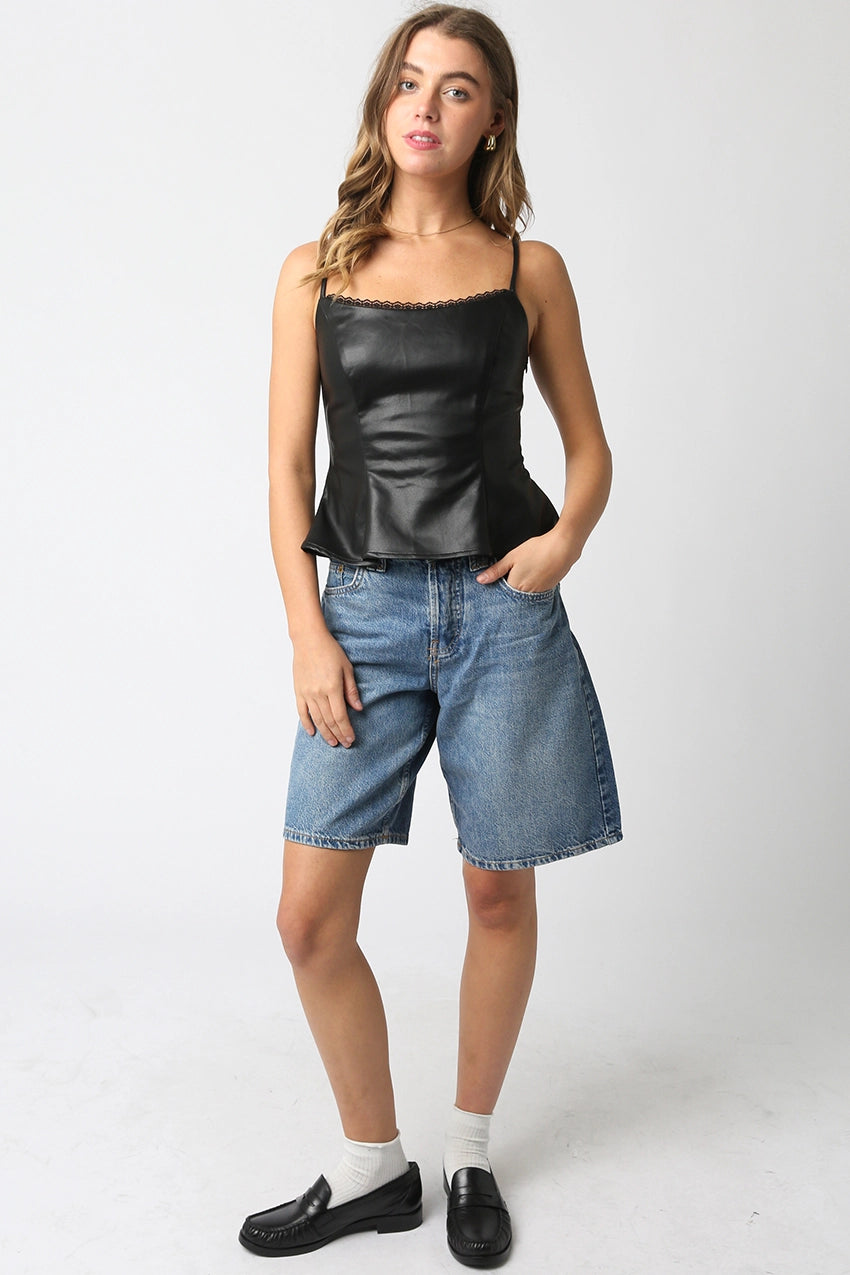 Woman wearing a black peplum top and blue denim shorts on a white background