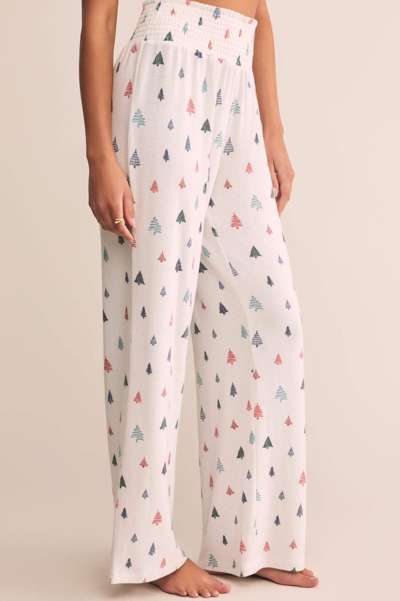 White pants with colorful tree pattern worn by a person on a beige background