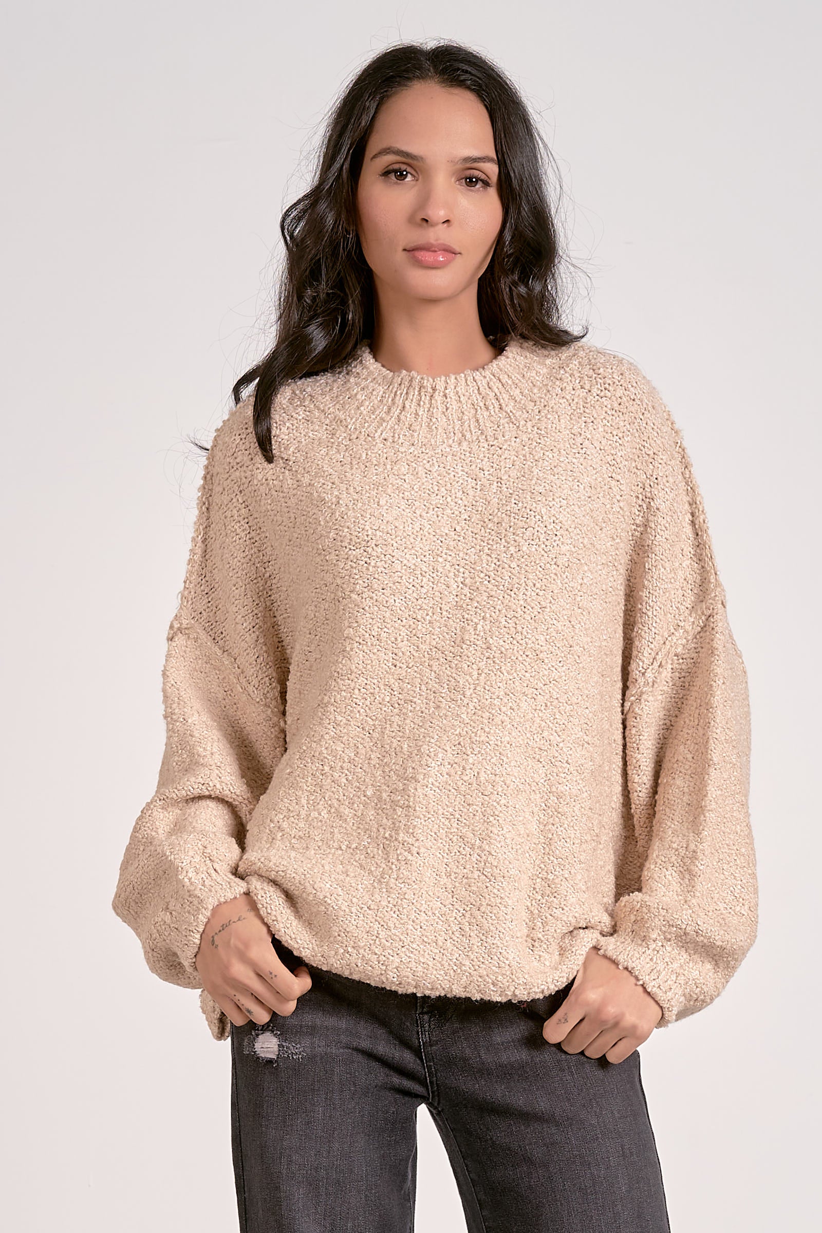Woman wearing a beige sweater against a white background