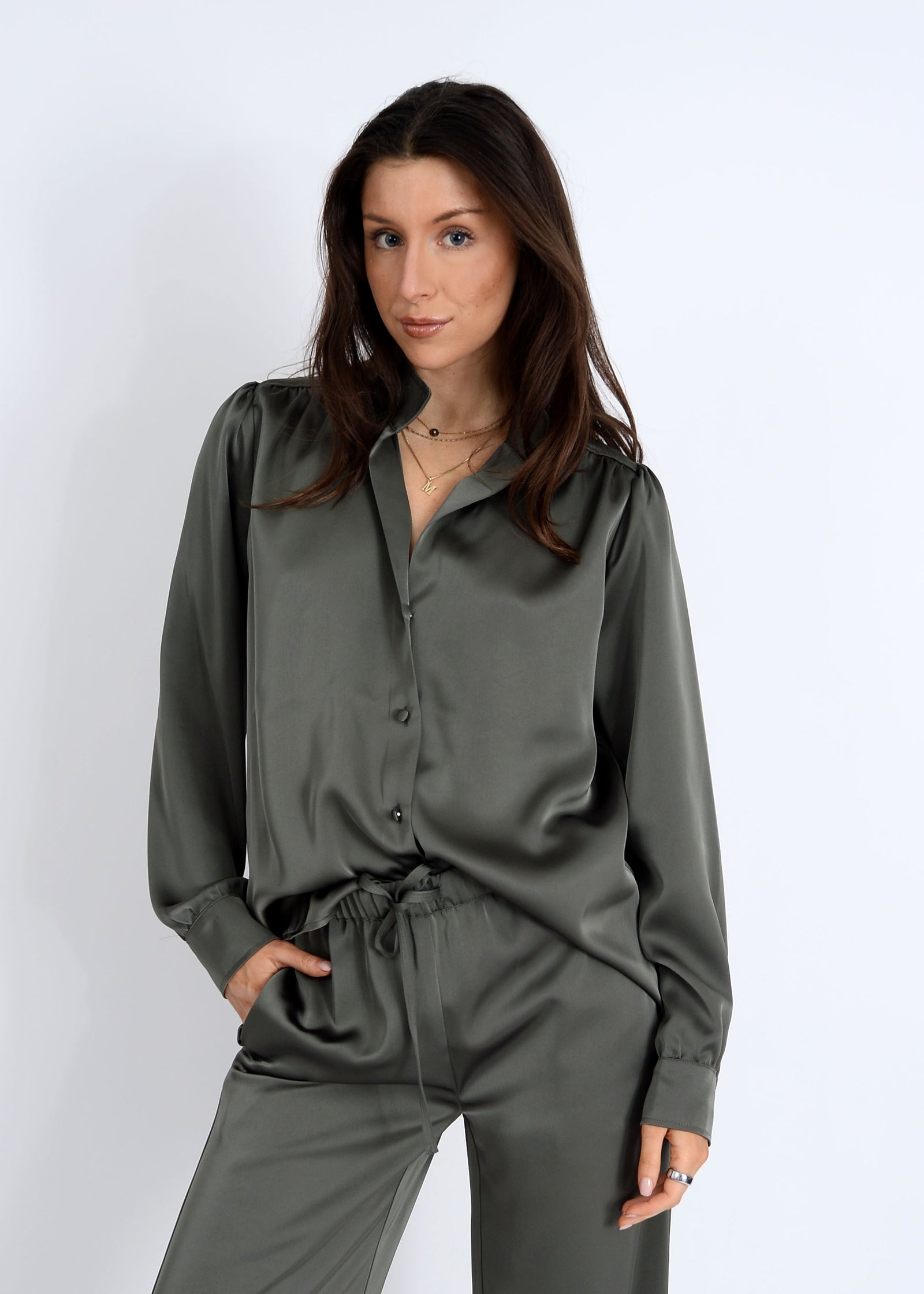 Woman wearing a green satin shirt and pants on a white background