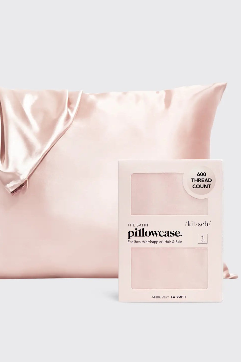 Pink satin pillowcase next to its packaging on a light gray background