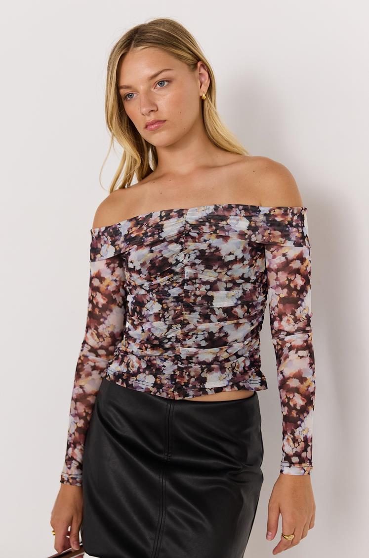 Woman wearing a floral off-shoulder top against a white background