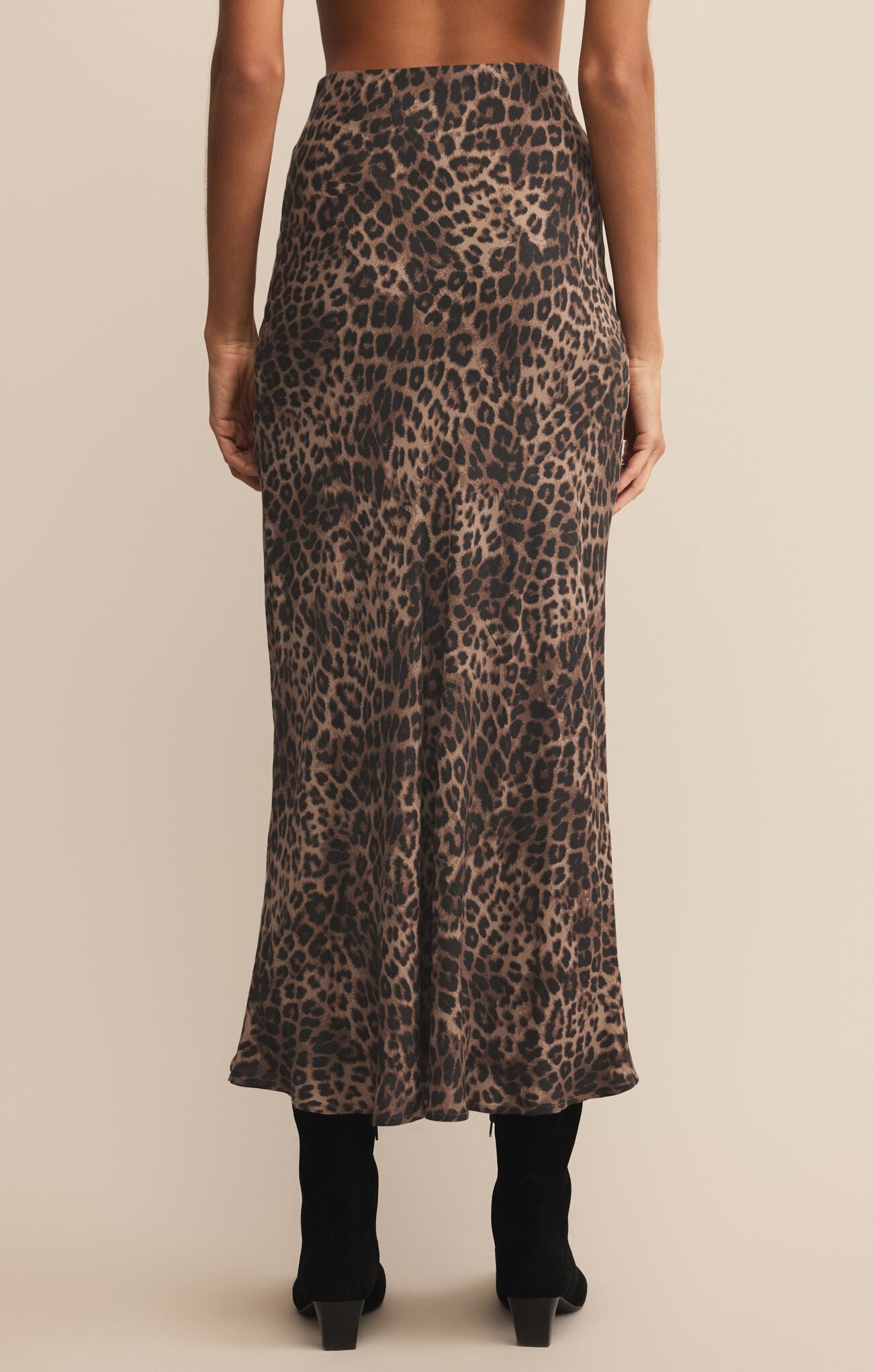 Person wearing a leopard print skirt on a beige background