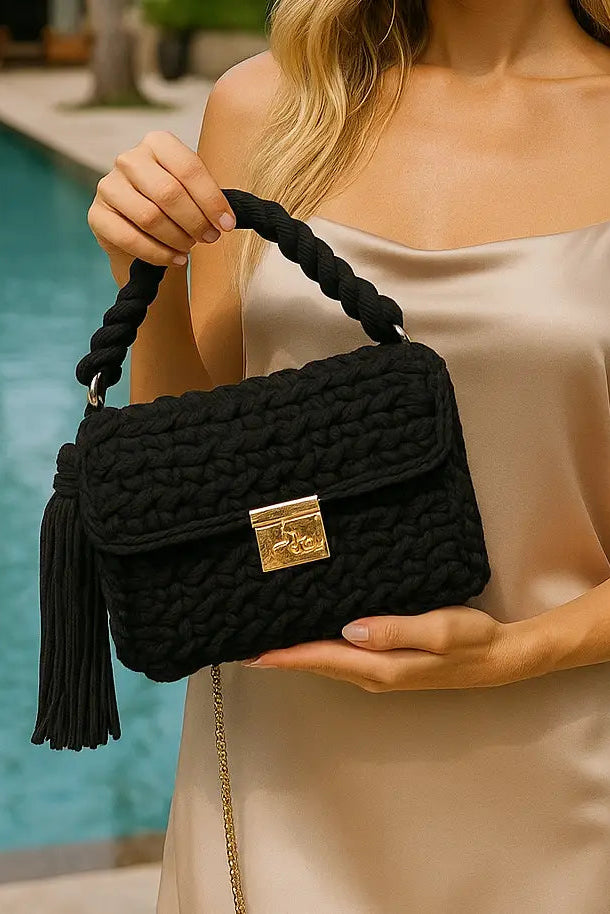 Woman holding a black textured handbag with a pool in the background