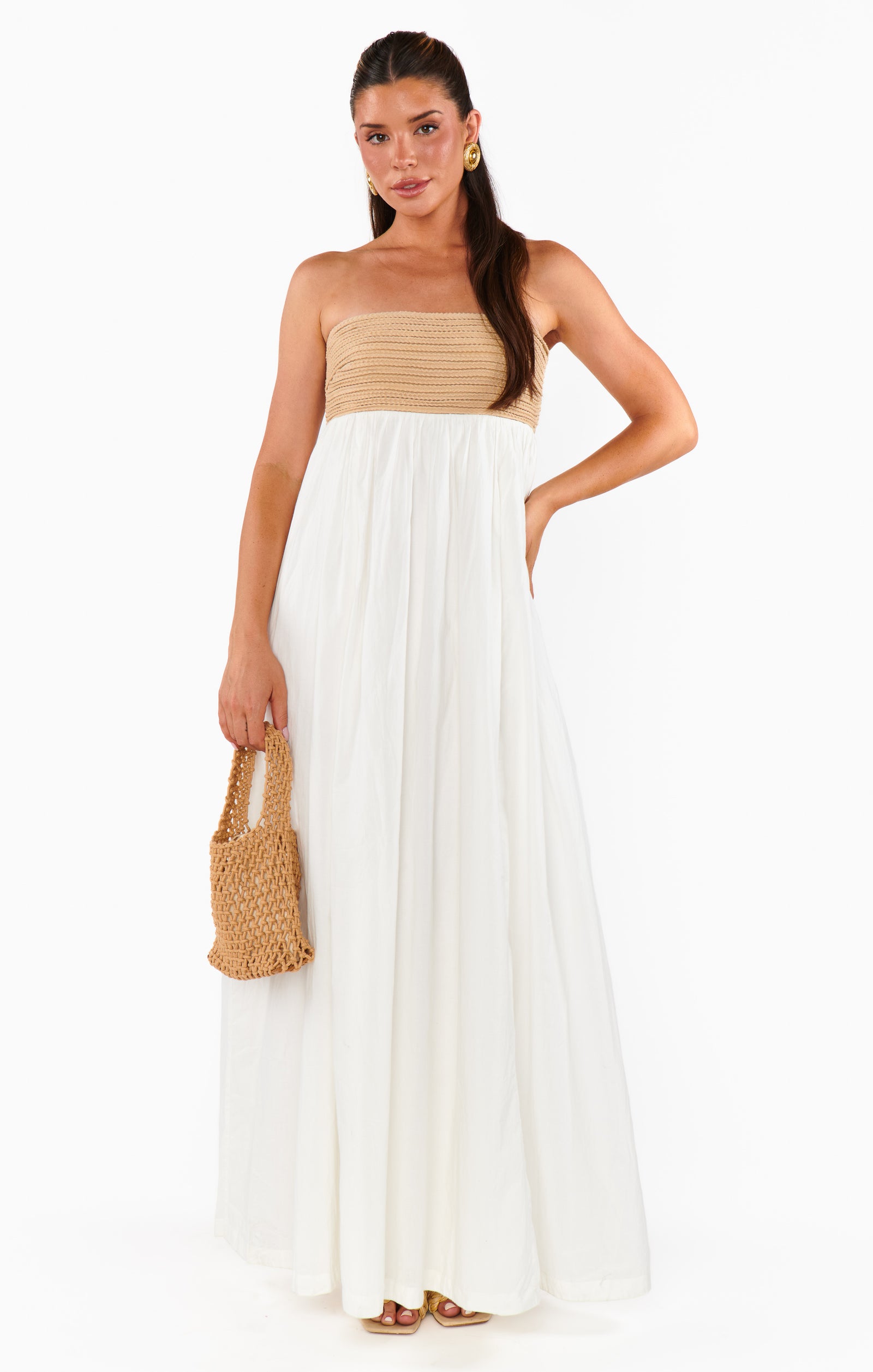 A woman wearing a white maxi dress with a twisted rope strapless design