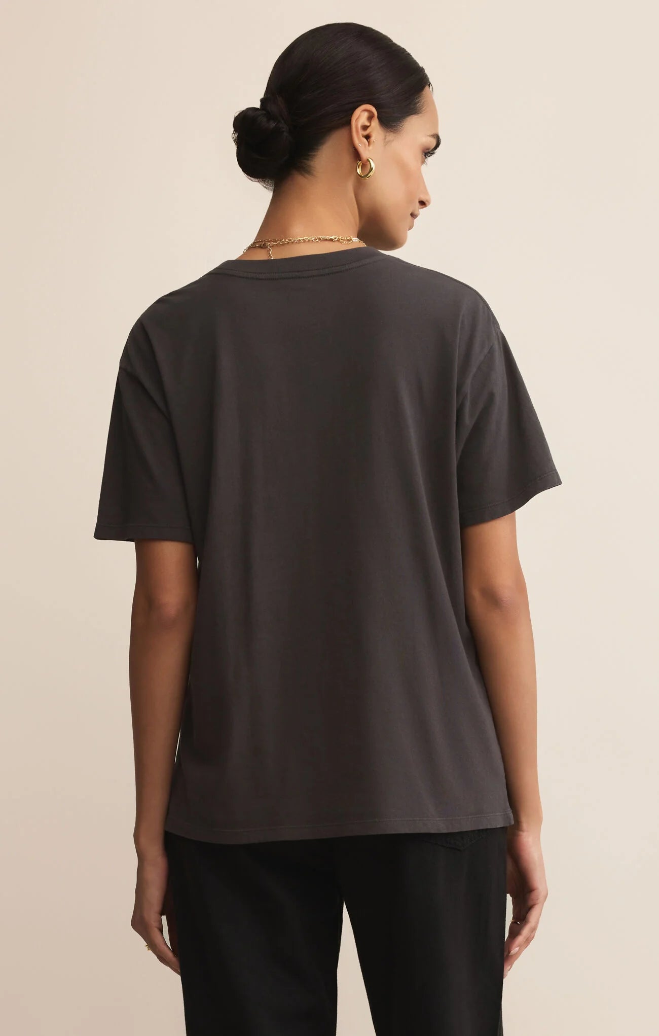 Woman wearing a black t-shirt against a beige background