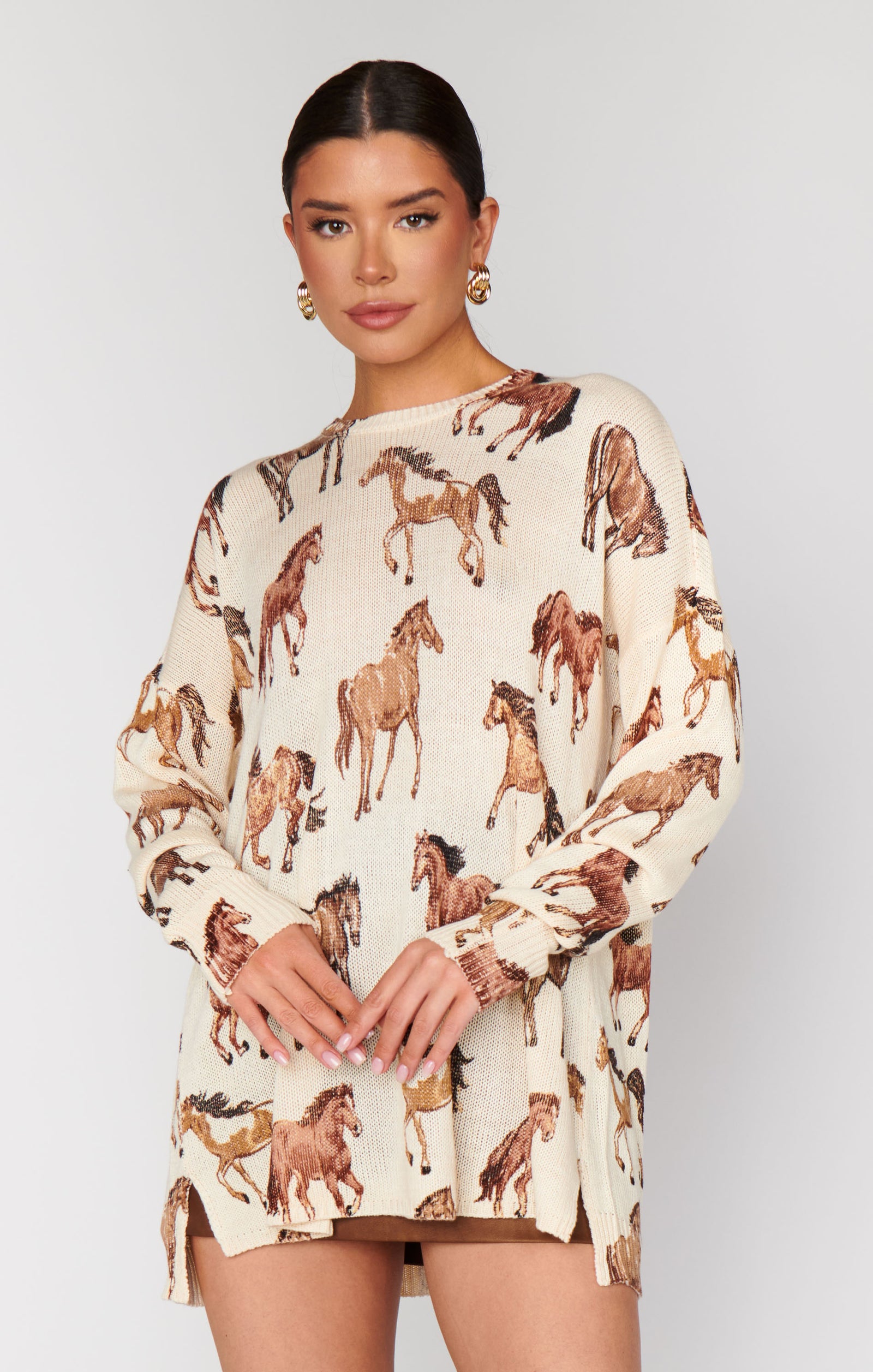 Woman wearing a cream-colored dress with horse prints on a plain background