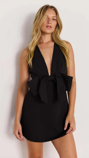 Woman wearing a black dress with a bow detail on a white background