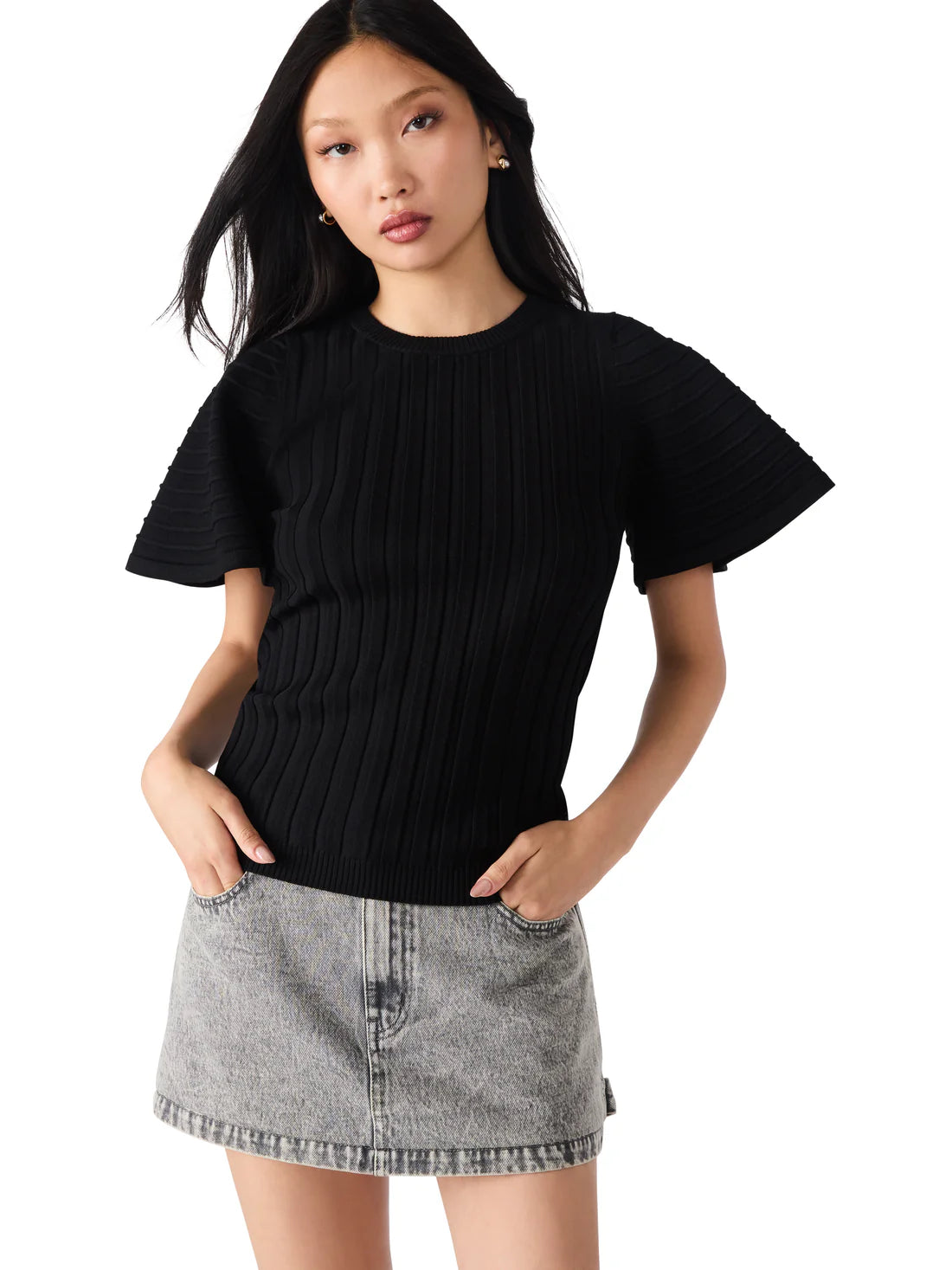 Woman wearing a black ribbed top and gray denim skirt on a white background