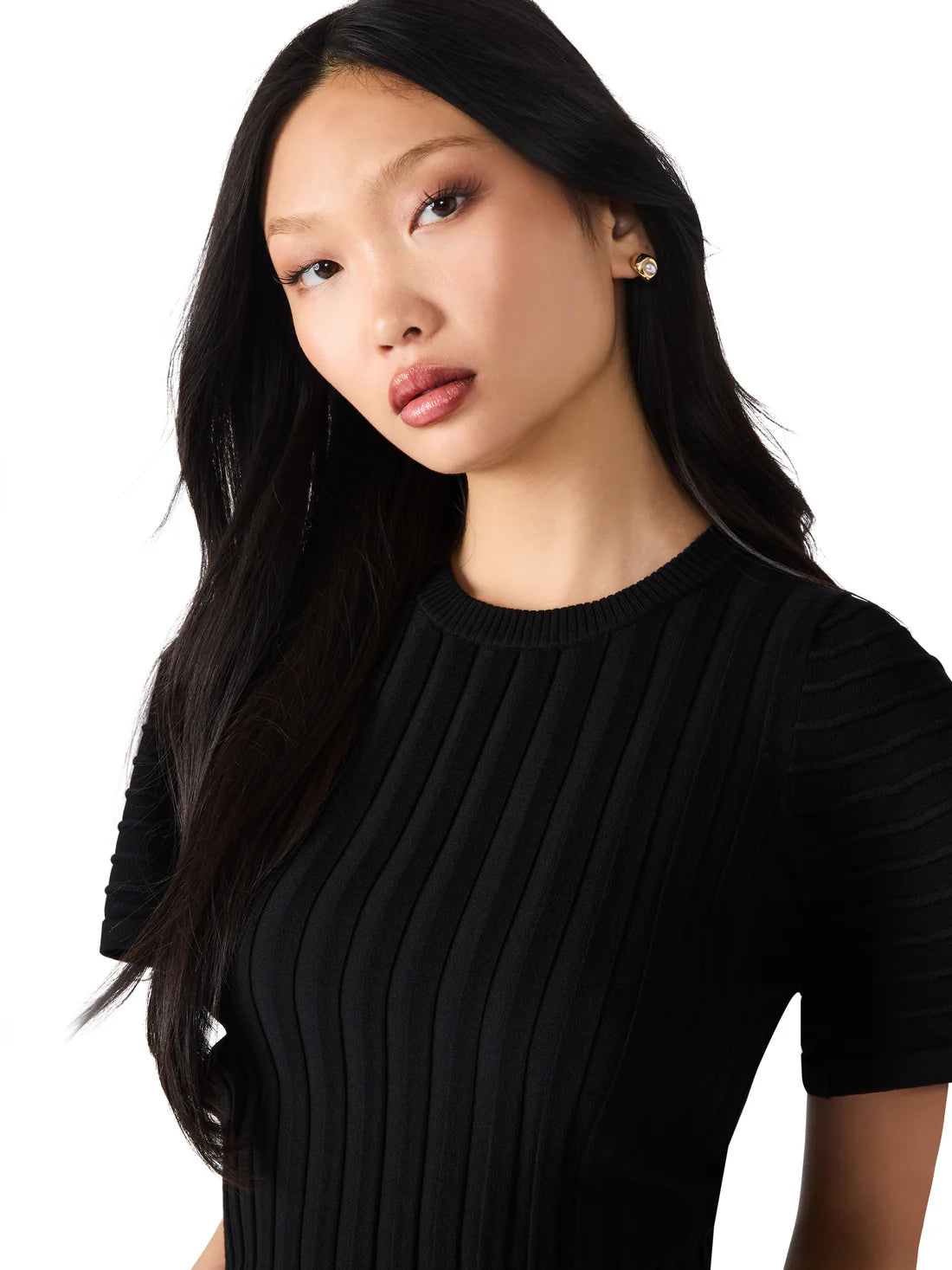 Woman wearing a black ribbed sweater against a white background