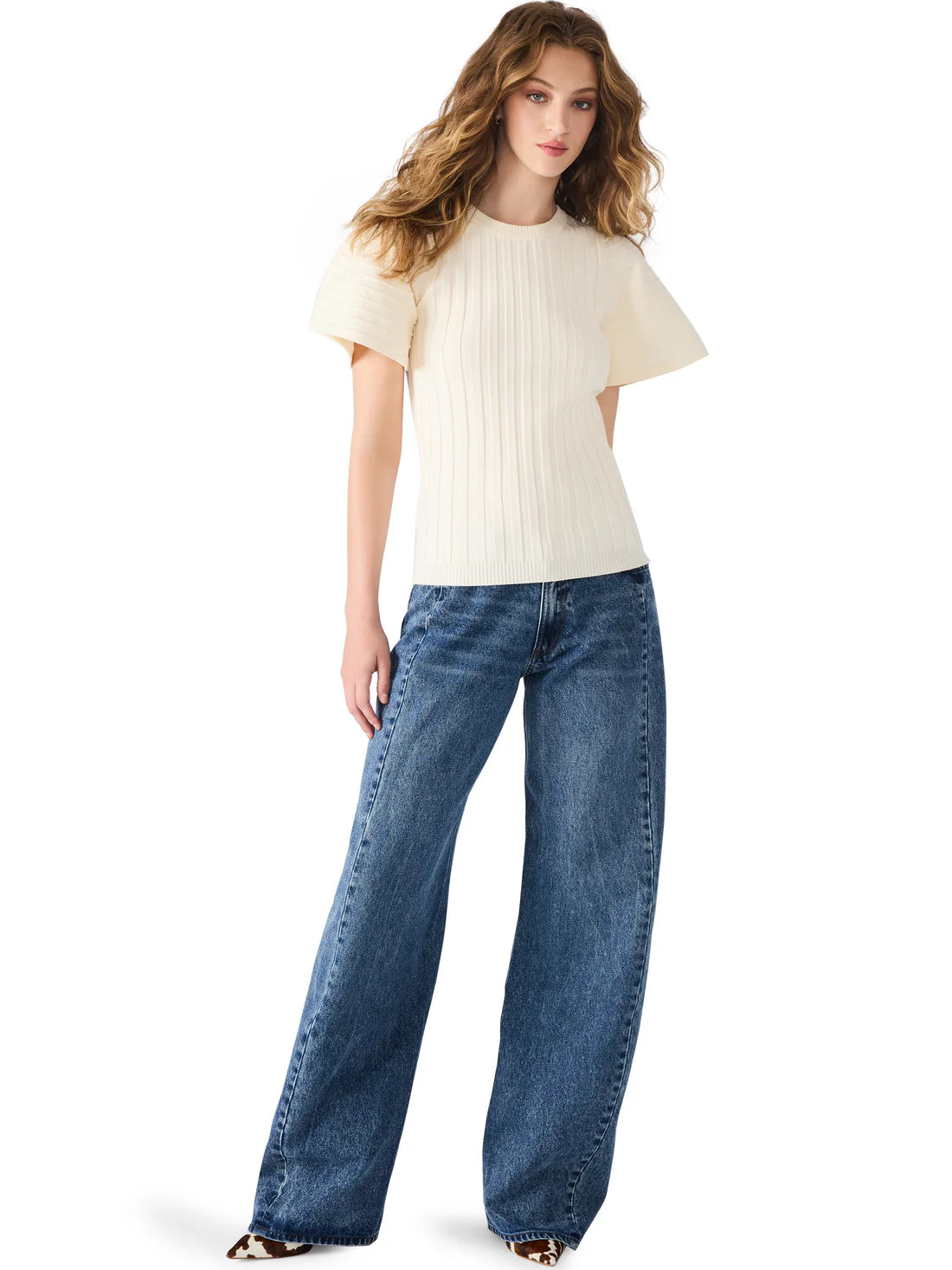 Woman wearing a white top and blue jeans on a white background