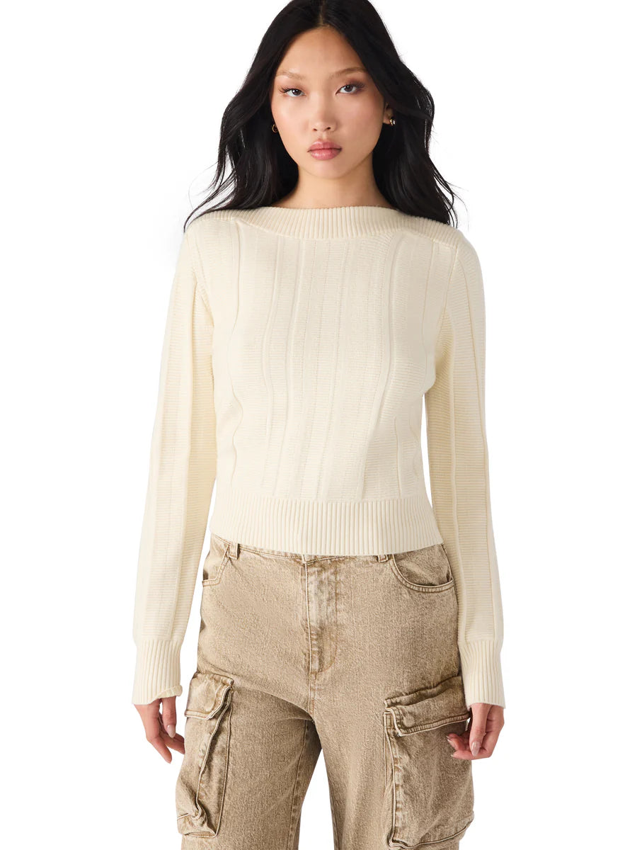Woman wearing a cream sweater and beige cargo pants on a white background