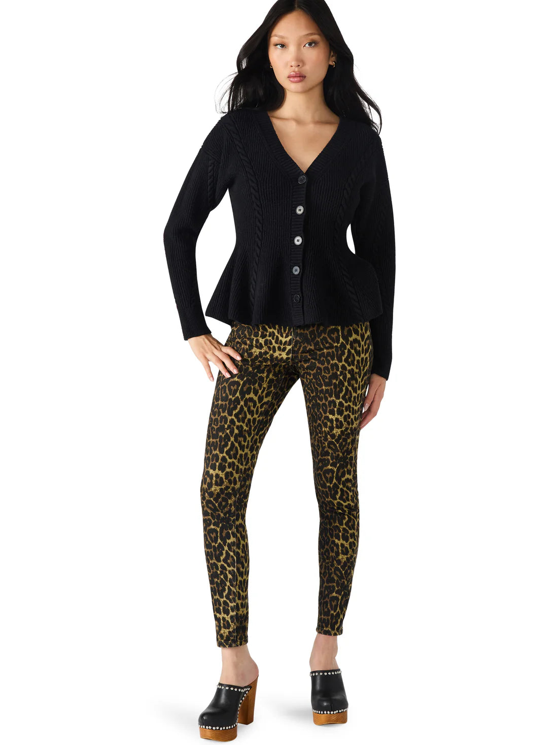 Woman wearing a black cardigan and leopard print pants on a white background