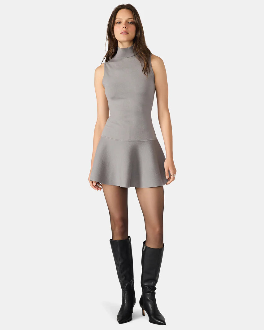 Woman wearing a gray dress with black knee-high boots on a white background