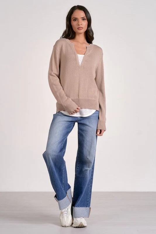 Woman wearing a beige sweater and blue jeans on a white background