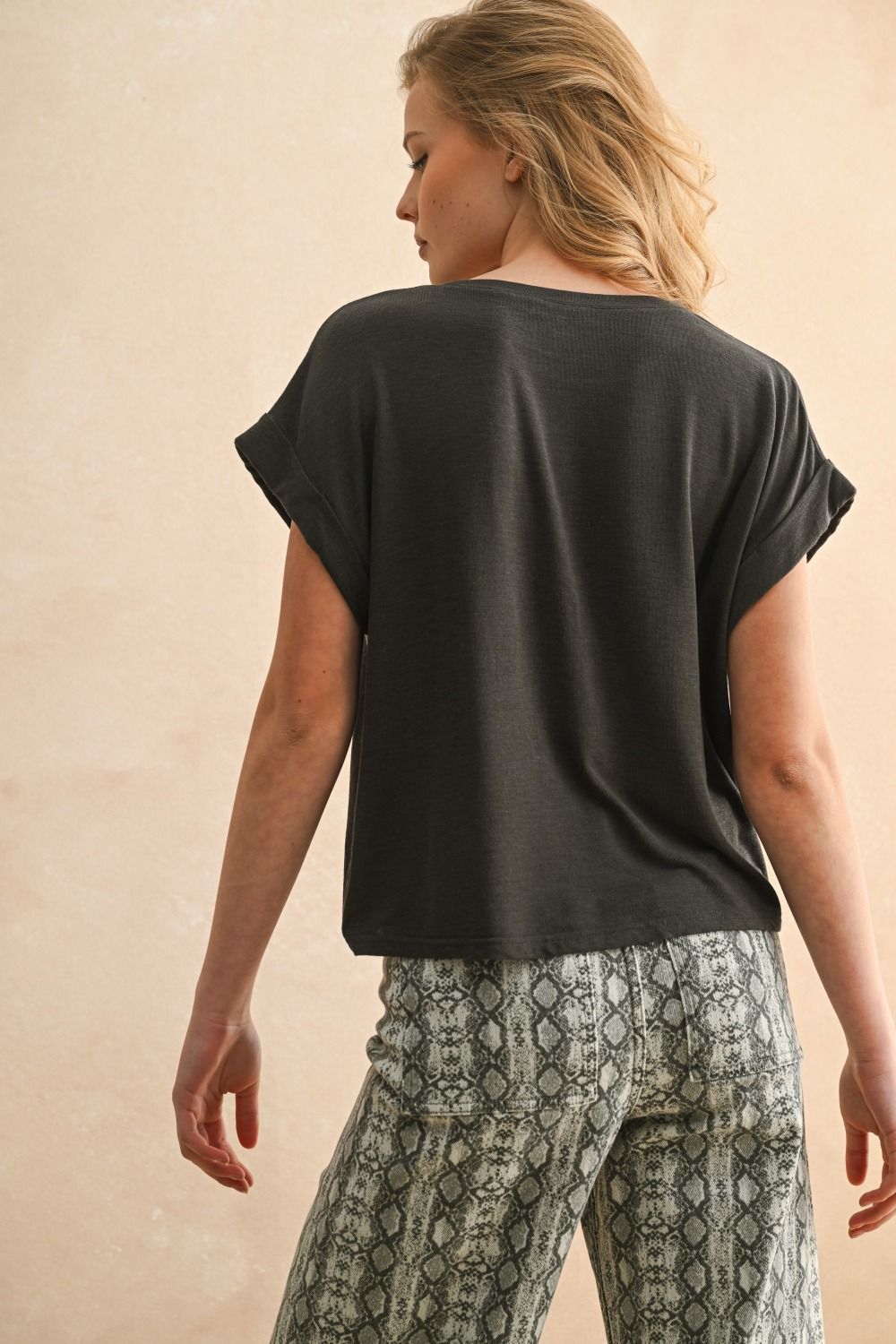 Woman wearing a black top and patterned pants on a beige background