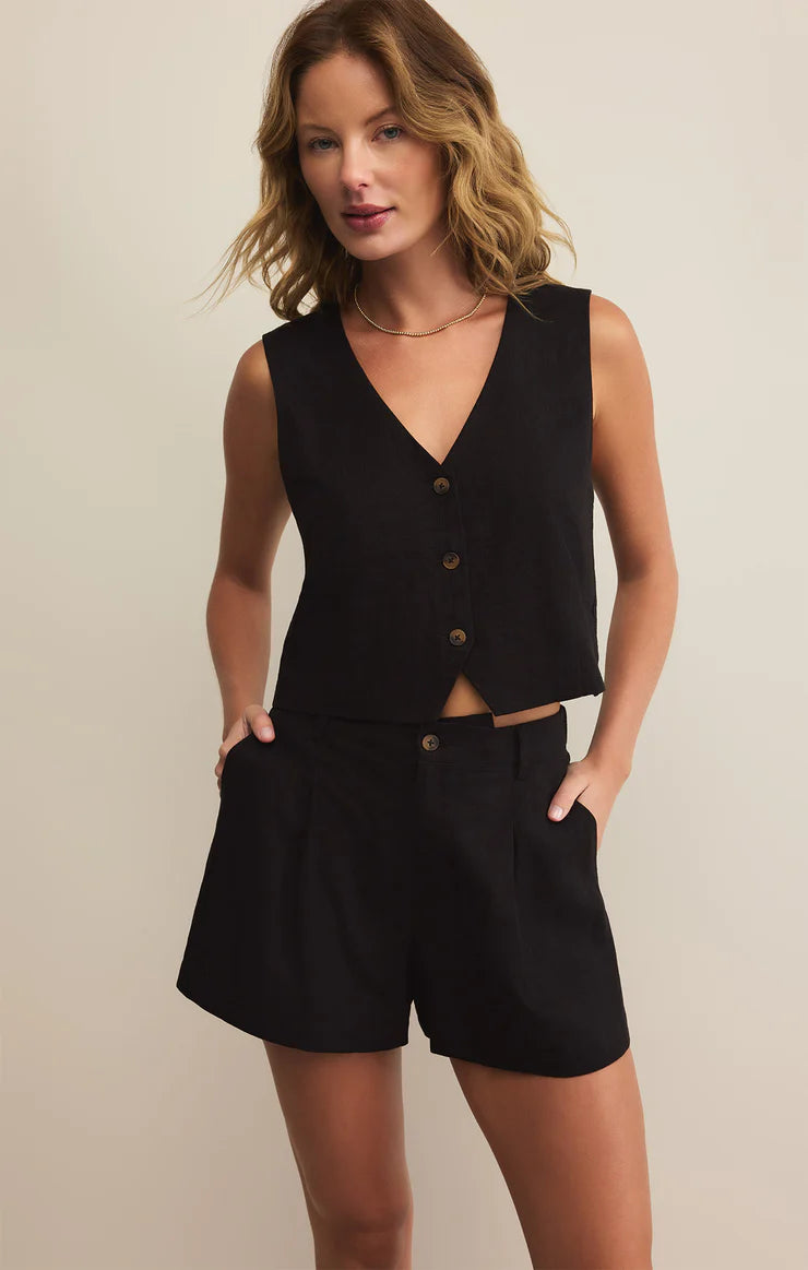 Woman wearing a black vest and shorts against a plain background