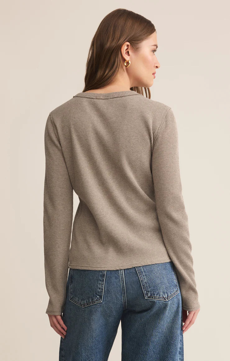 Woman wearing a beige sweater and blue jeans on a beige background