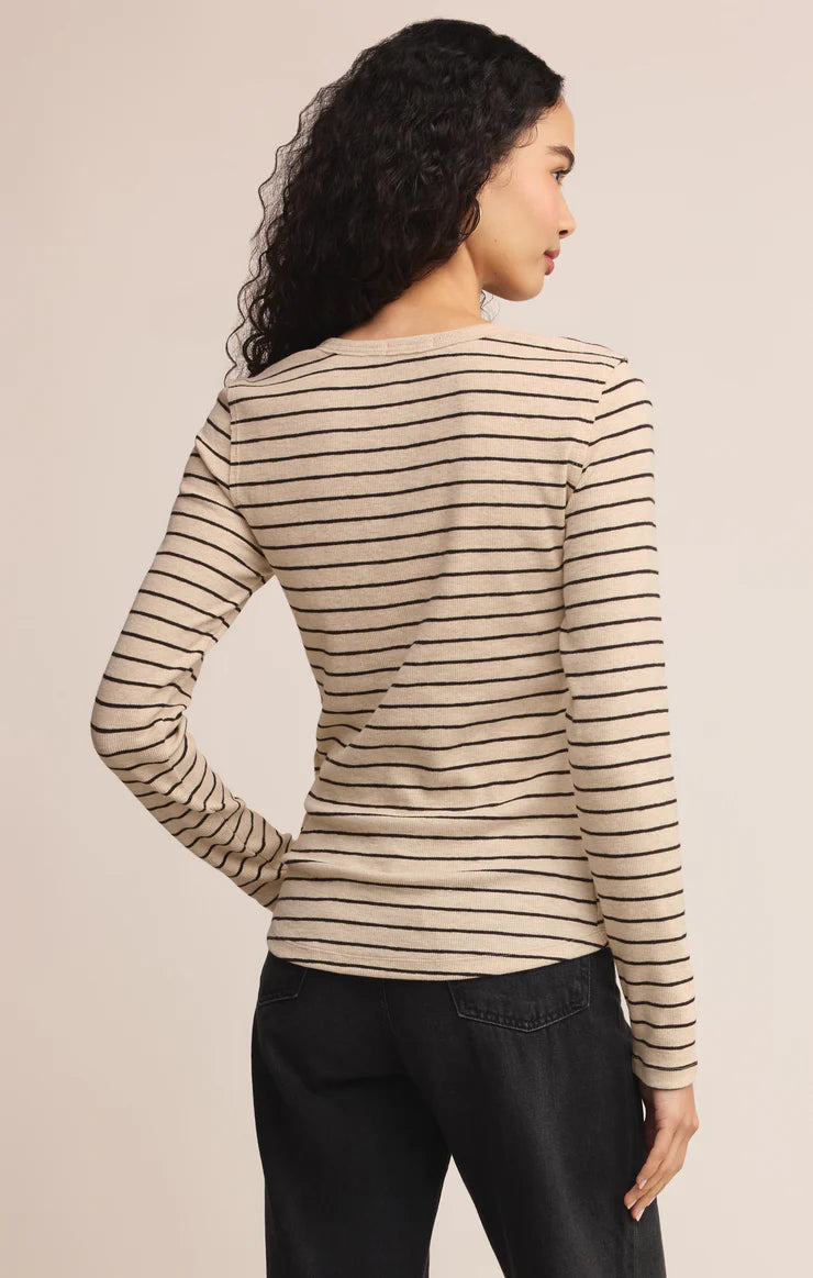 Woman wearing a striped long-sleeve top against a beige background