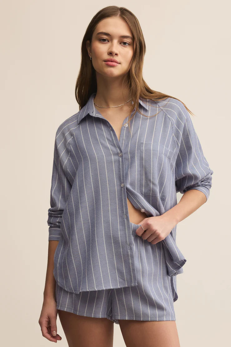 Woman wearing a blue striped shirt and shorts set on a beige background
