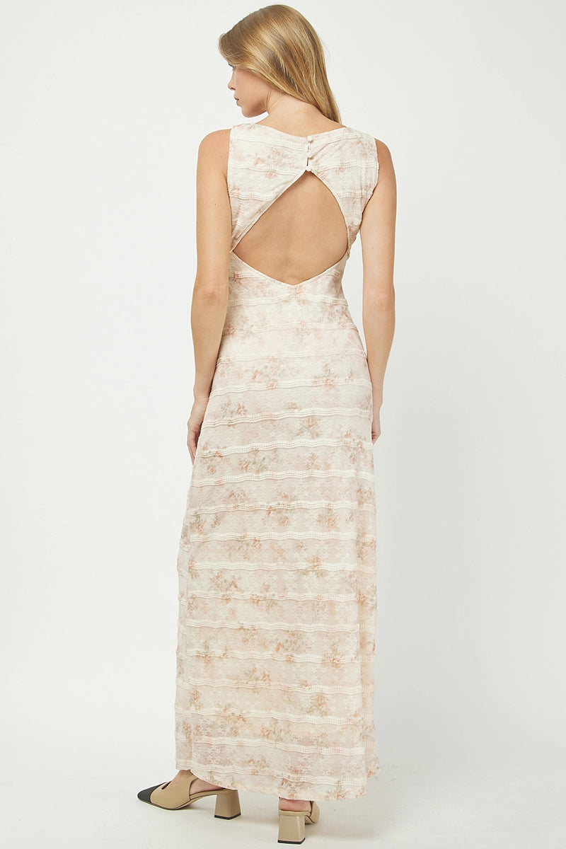 Woman wearing a long, patterned dress with an open back on a white background