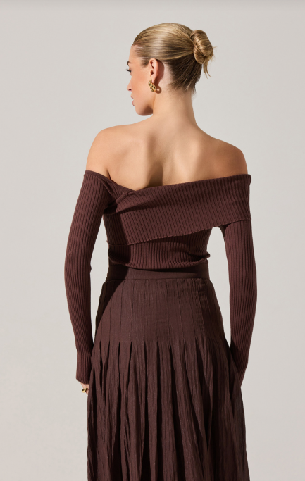 Woman wearing a brown off-shoulder dress against a plain background