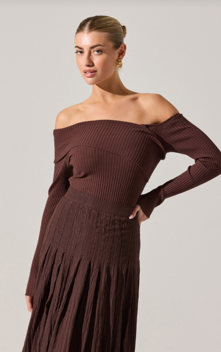 Woman wearing a brown off-shoulder dress against a plain background