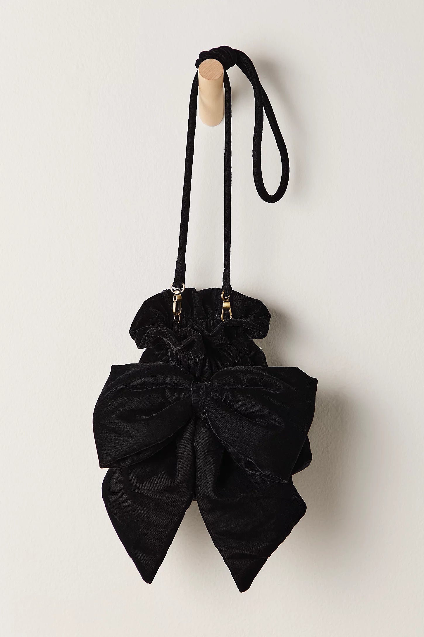 Black bow-shaped handbag with a strap on a light beige background