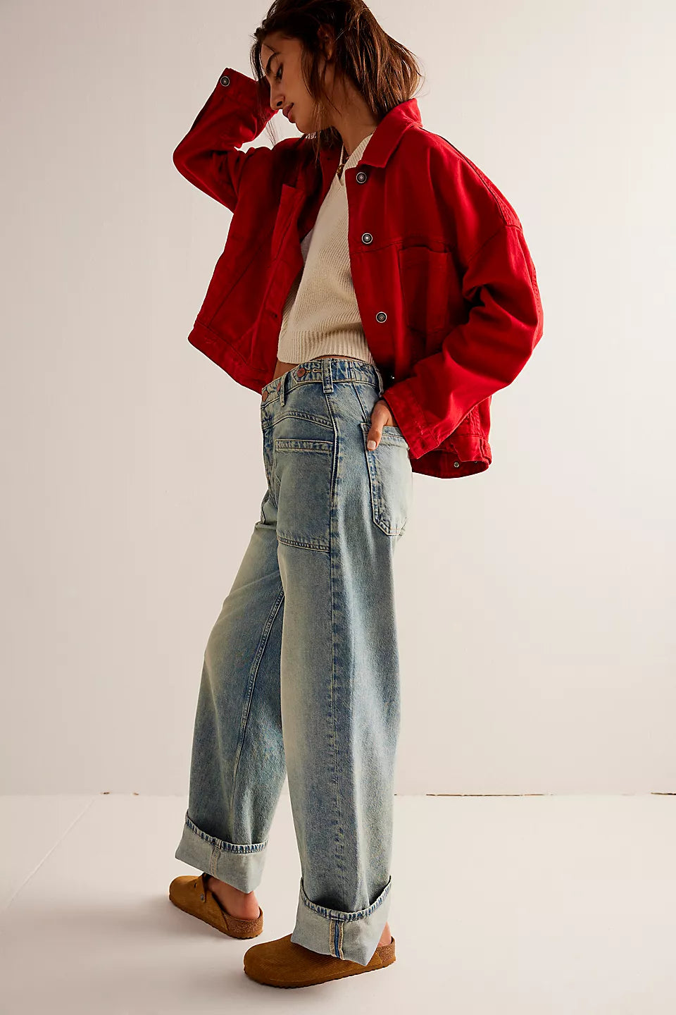 Person wearing a red jacket and blue jeans on a plain background