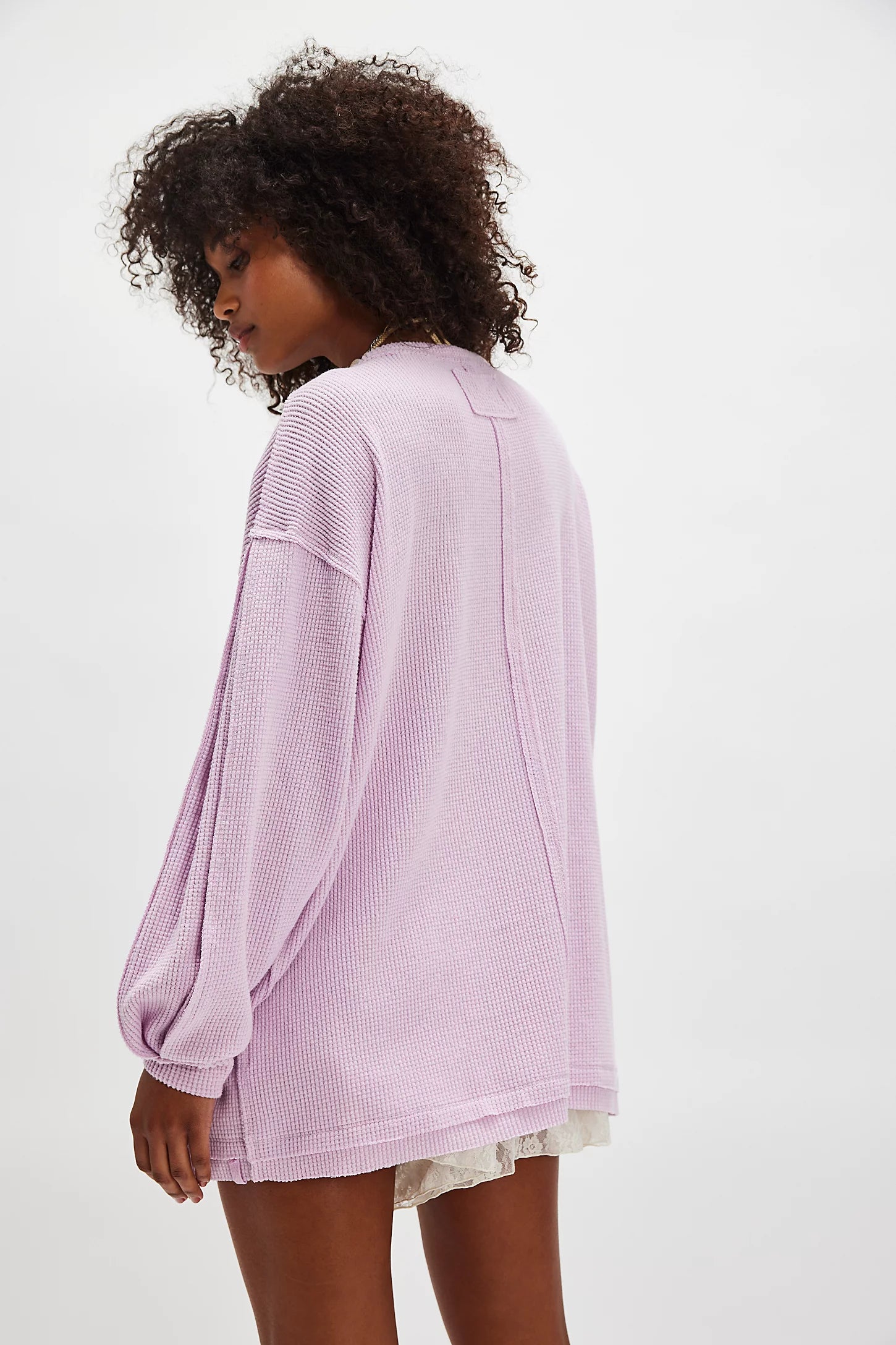 Person wearing a light purple oversized sweater on a white background