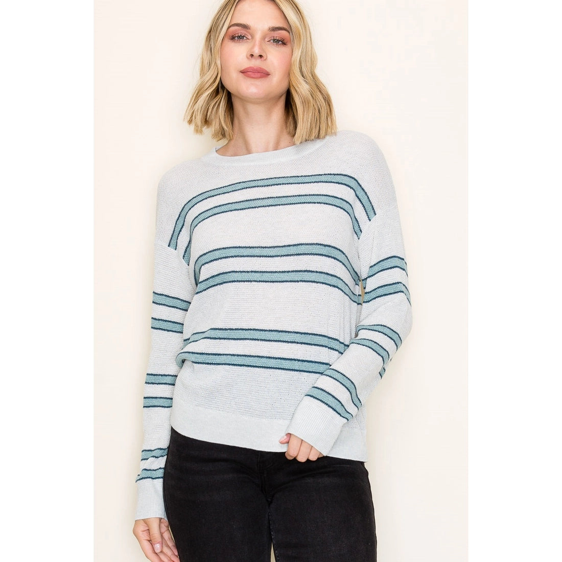 Woman wearing a light blue and white striped sweater on a beige background