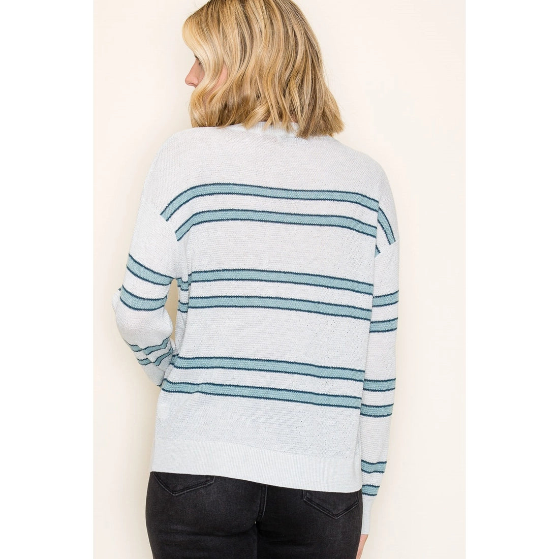 Woman wearing a light blue and white striped sweater on a plain background