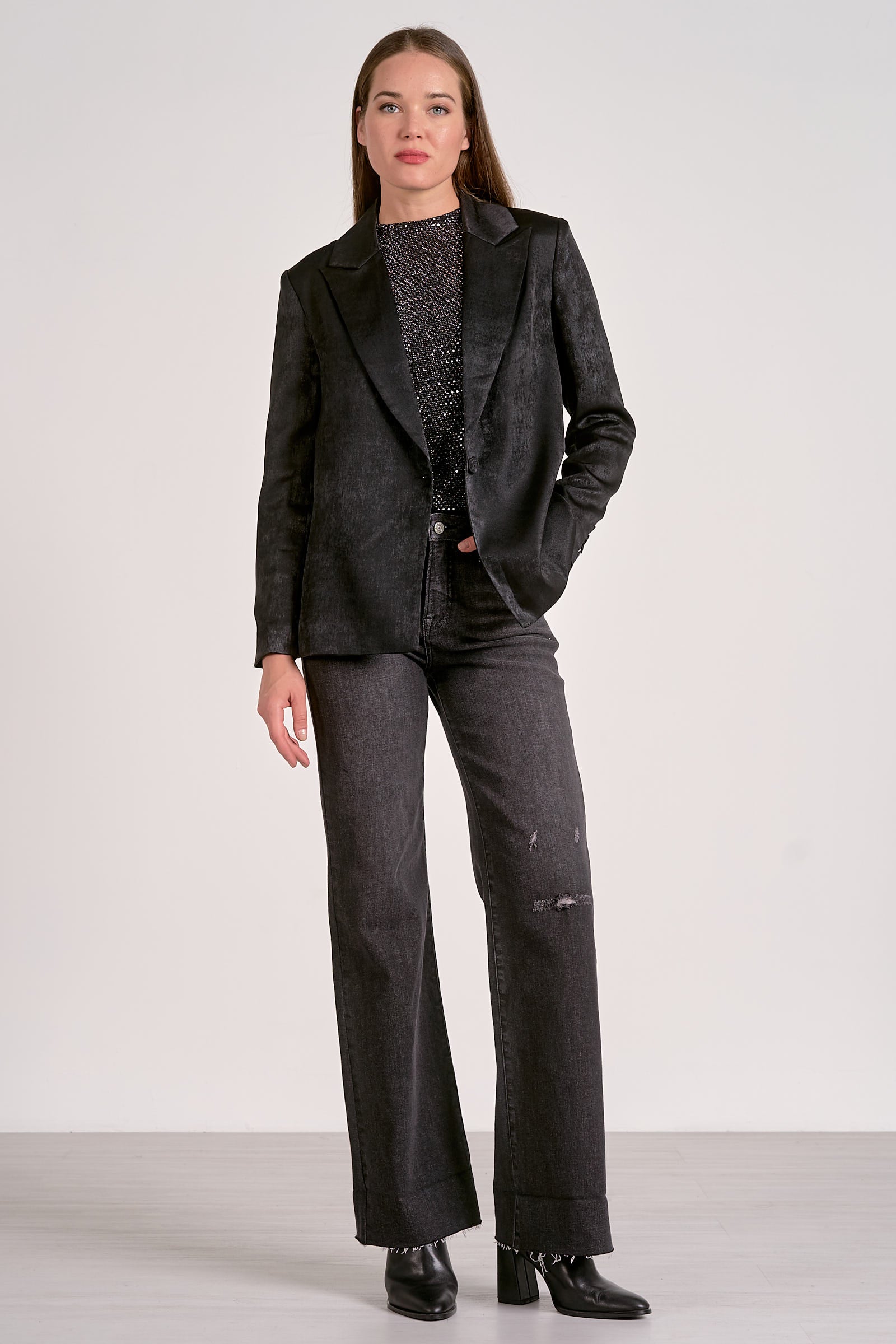 Woman wearing a black blazer and gray pants on a white background
