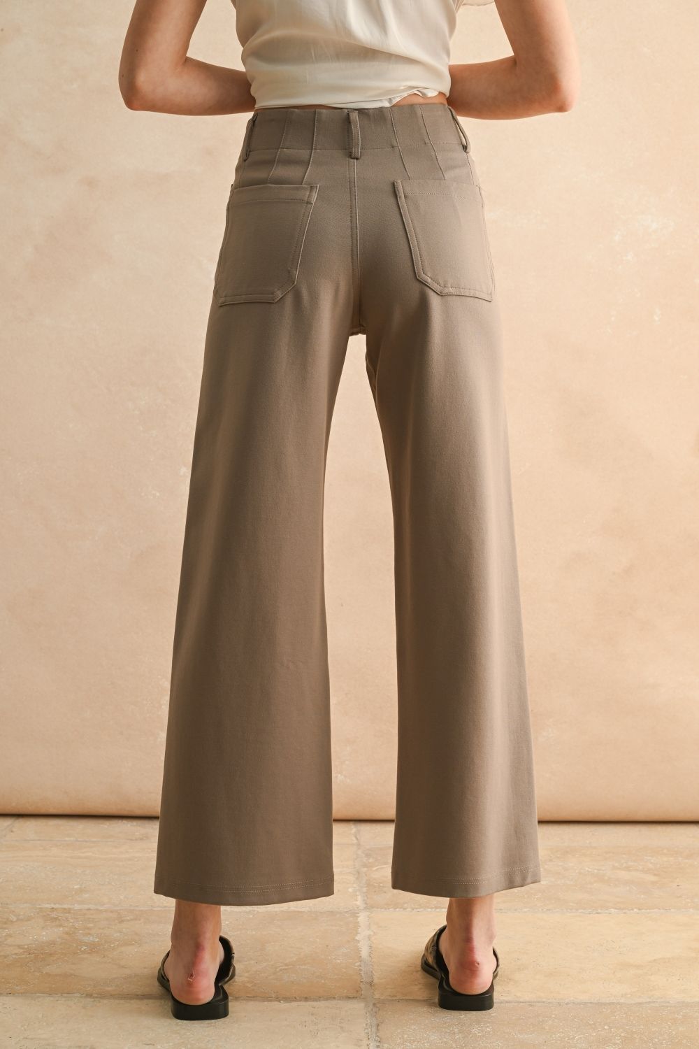 Person wearing beige wide-leg pants against a beige background