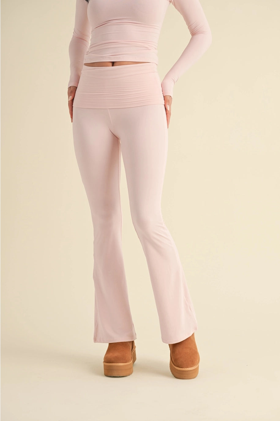 Person wearing a light pink outfit with flared pants on a beige background