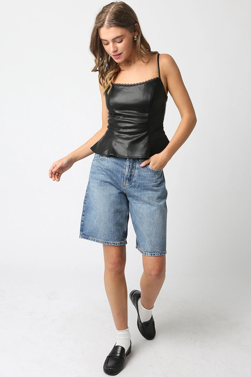 Woman wearing a black peplum top and blue denim shorts on a white background
