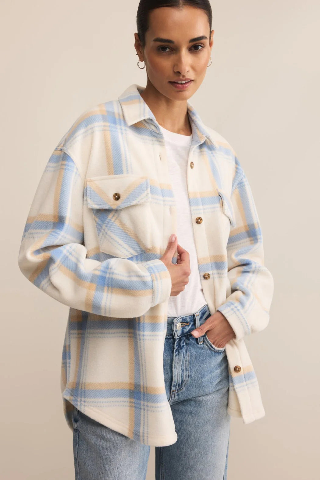 Woman wearing a plaid shirt with blue and beige stripes on a plain background