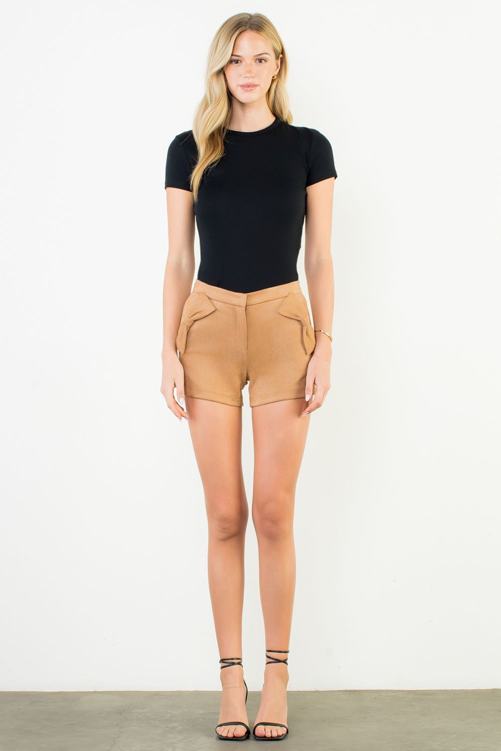 Woman wearing a black t-shirt and tan shorts on a white background