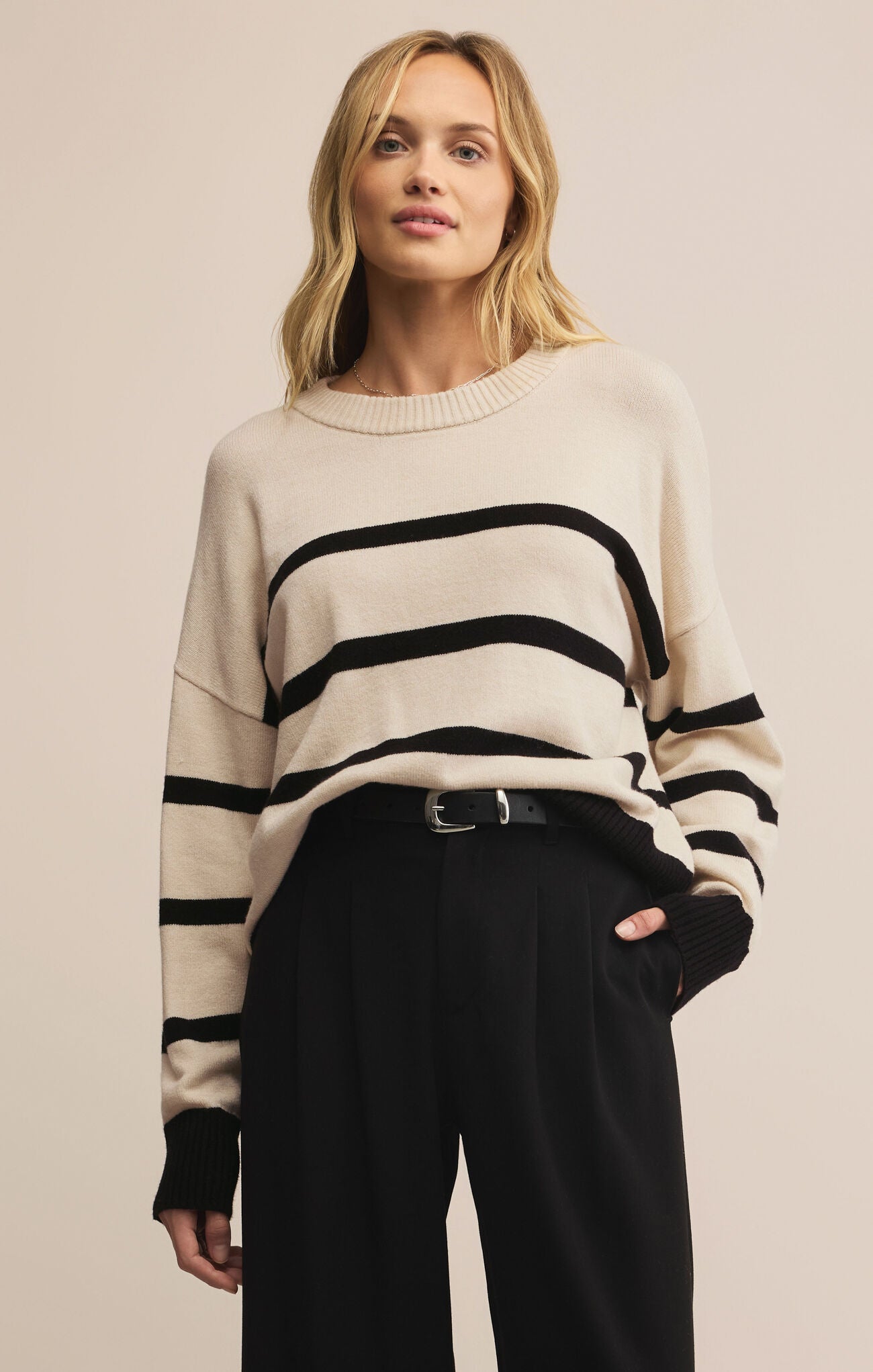 Woman wearing a cream sweater with black stripes on a beige background