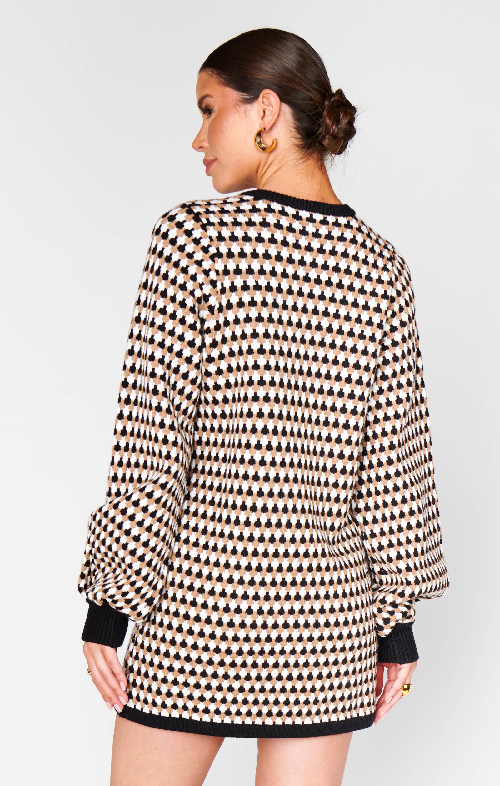 Woman wearing a patterned dress with long sleeves on a plain background