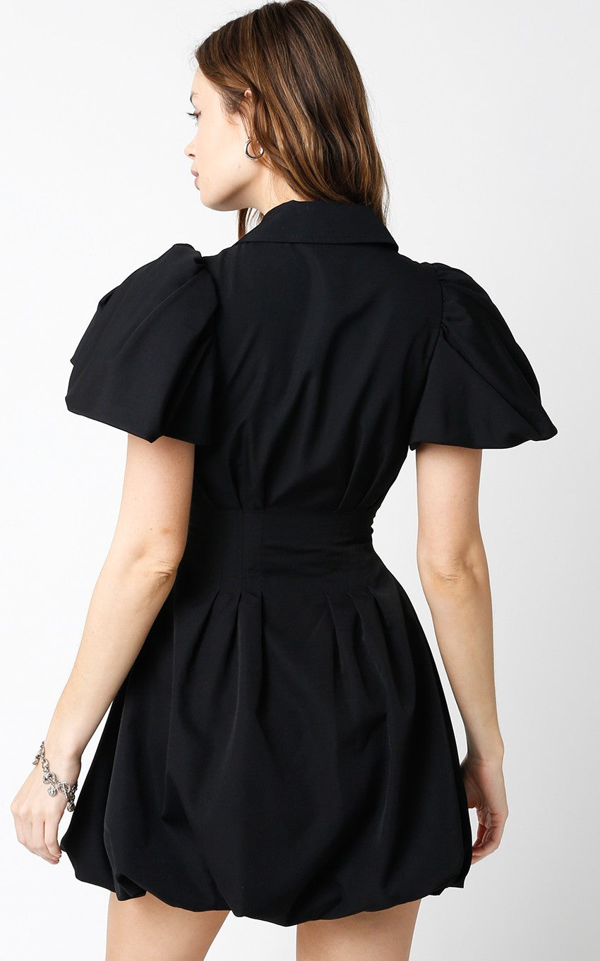 Woman wearing a black dress with puffed sleeves on a white background