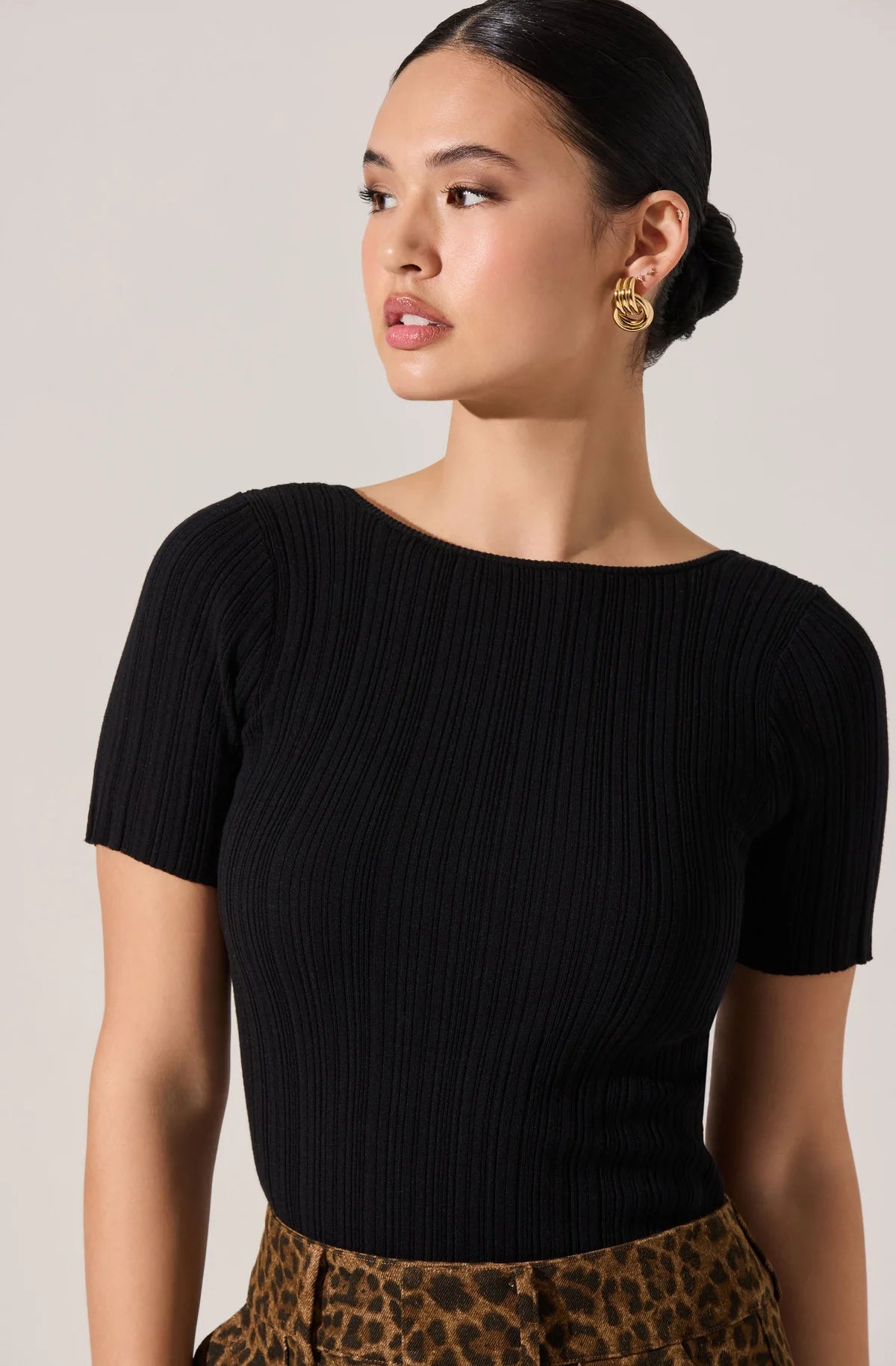 Woman wearing a black ribbed top with a neutral background