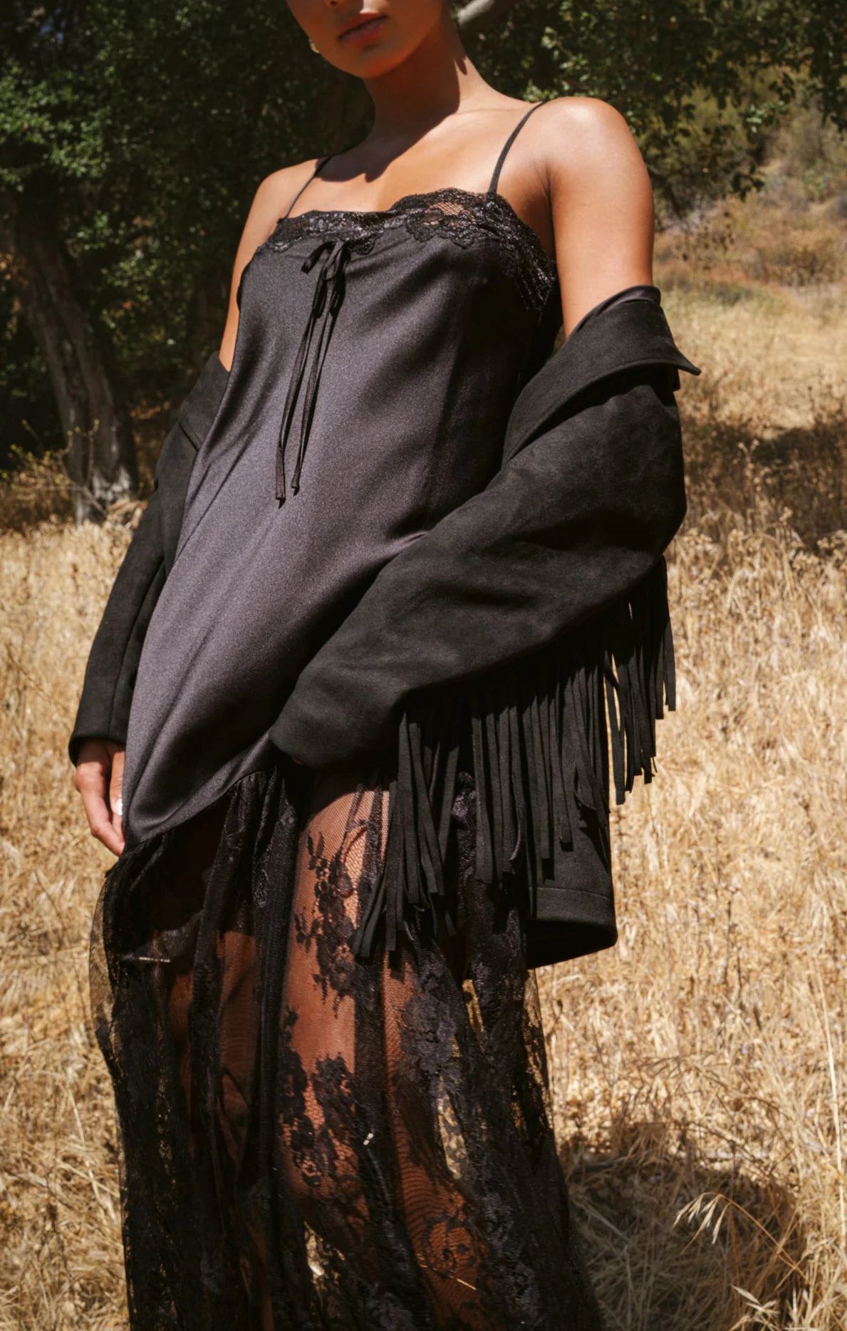 Person wearing a black fringe garment in a natural setting