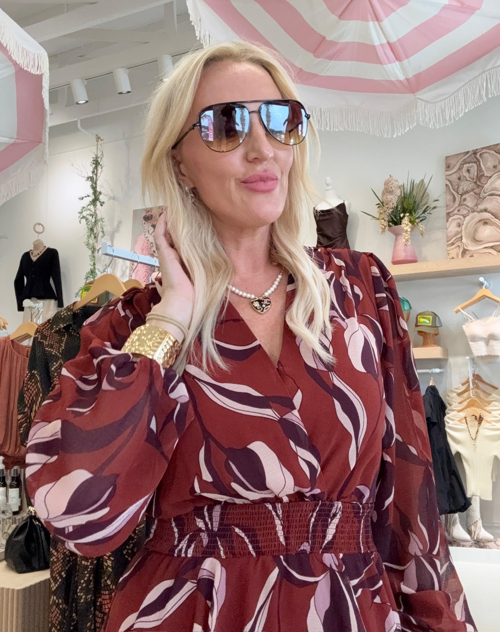Woman in a patterned dress with sunglasses in a store setting