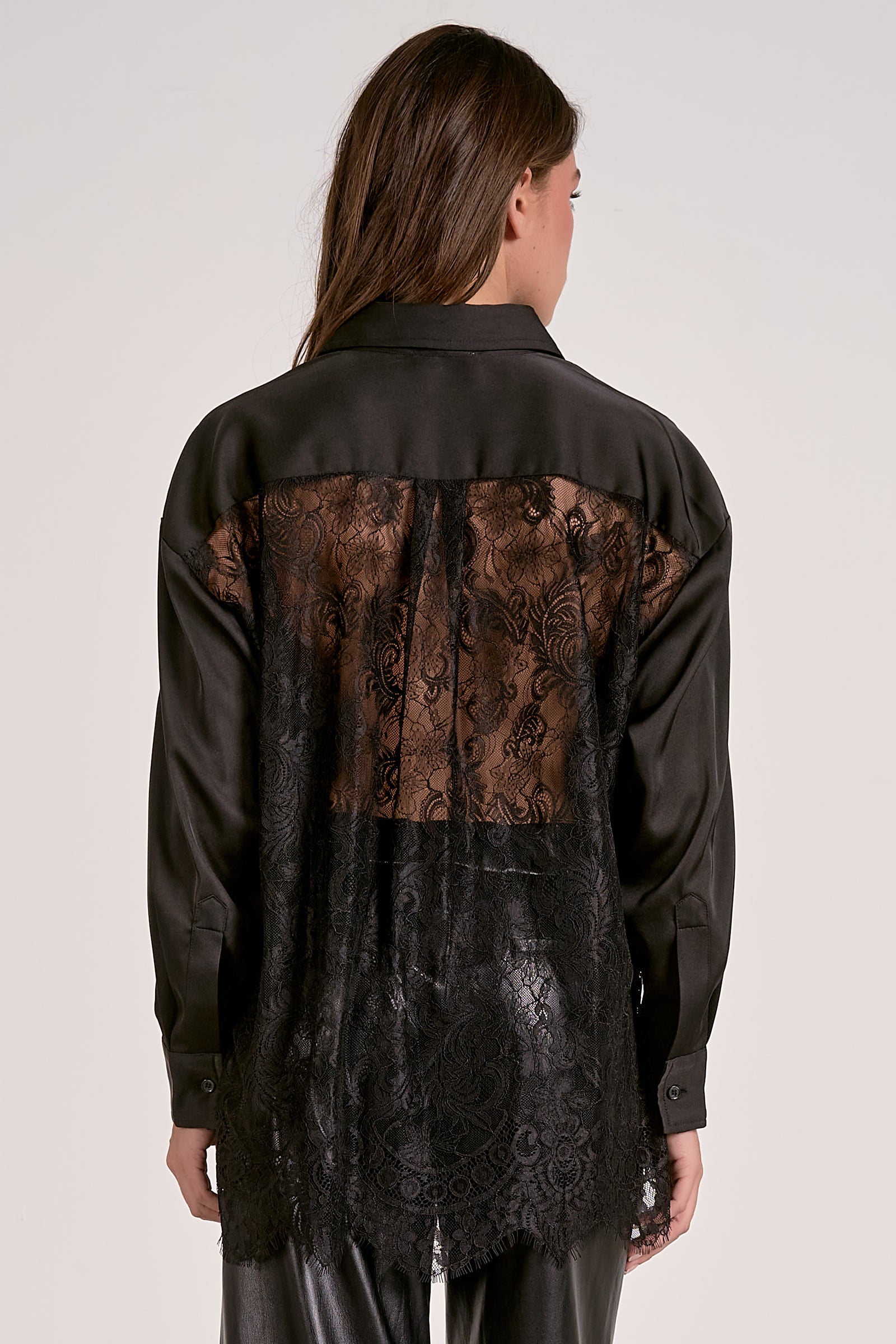 Black shirt with lace detailing on the back worn by a person against a white background